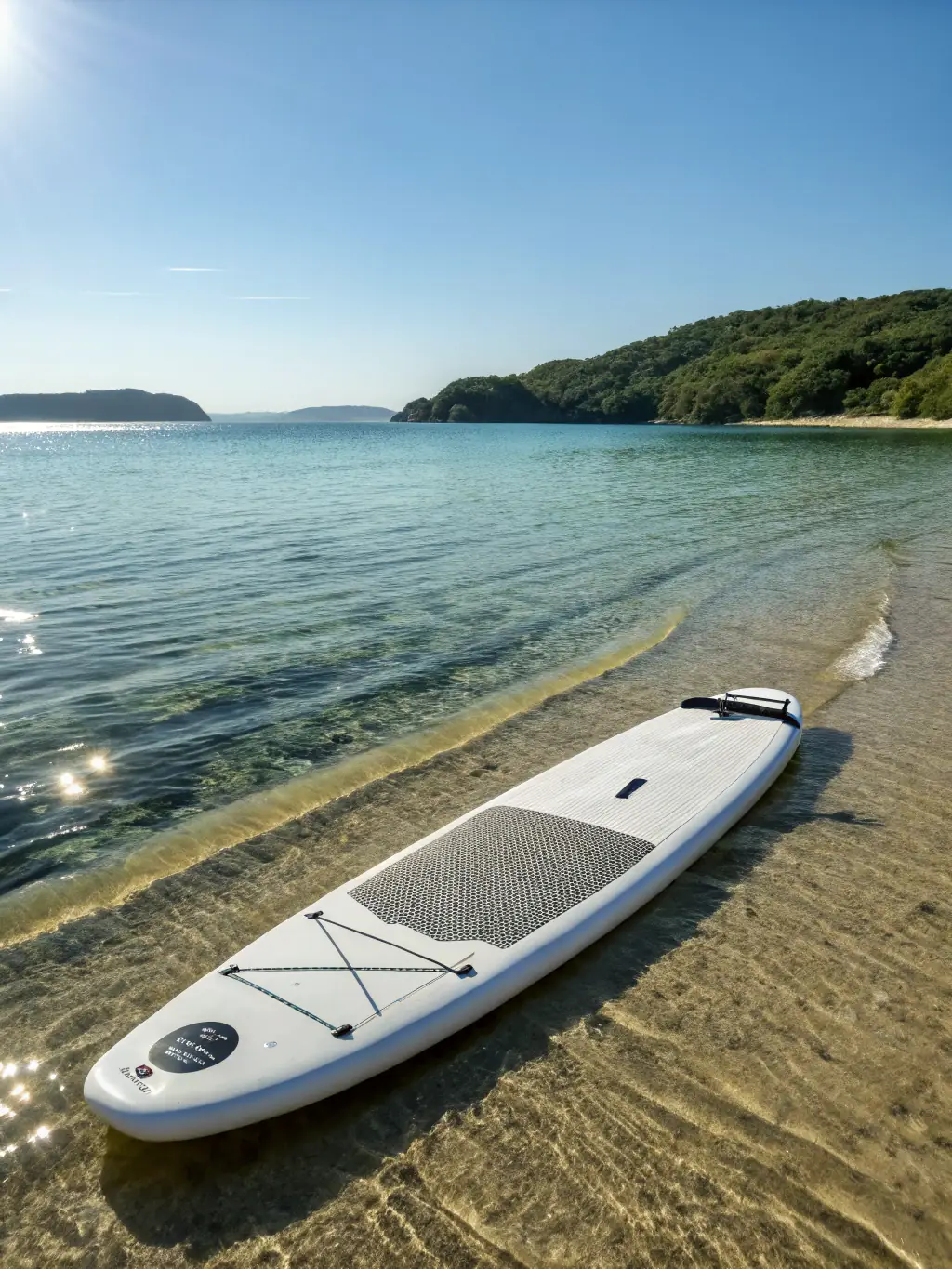 A person paddling a longboard in calm water, demonstrating the ease of paddling and catching waves with a larger board. The background shows a serene beach with gentle waves.